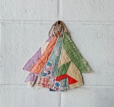 several colorful pieces of fabric hanging on a wall with white brick walls behind them and a string attached to the top of each piece