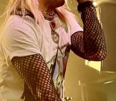 a man with long hair holding a microphone in his hand and wearing fishnet stockings