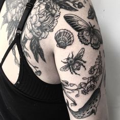 the back of a woman's arm with tattoos on it and flowers, bees, and honeycombs