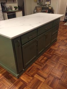 a large kitchen island with marble top and green cabinets