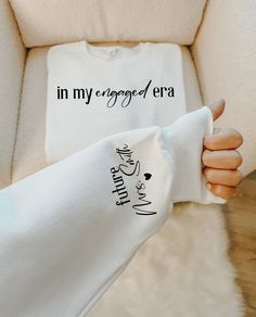 a woman's hand holding onto a white shirt that says in my engaged era