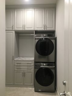 a washer and dryer are in the corner of this laundry room with white cabinets