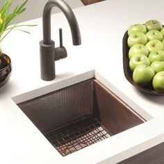 a sink with some apples in it next to a bowl of green apples