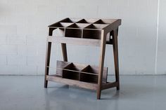 a wooden shelf with three compartments on it in front of a white brick wall and floor