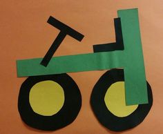 a paper cut out of a green tractor on an orange background with black circles around the wheels