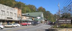 cars are parked in front of buildings on the side of a road with a sign that says chimney rock