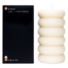 a white candle sitting next to a black box with the words citrus lime and pettigrain on it