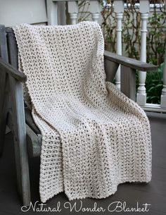 a white crocheted blanket sitting on top of a wooden chair next to a porch