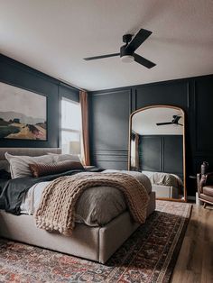 a bedroom with black walls and a large bed in front of a mirror on the wall