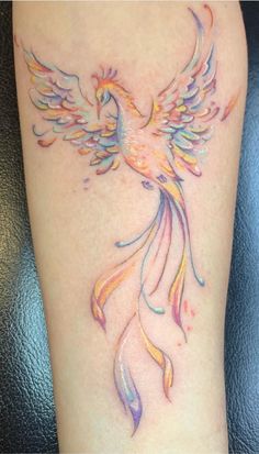 a colorful tattoo on the leg of a woman with a bird in it's wings