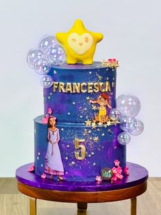 a three tiered cake decorated with princesses and bubbles is on a table in front of a white wall