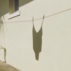 the shadow of a woman's dress on a clothesline is shown against a white wall