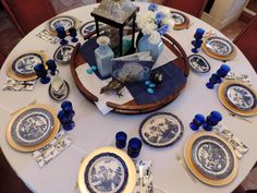 the table is set with blue and white plates, napkins, and vases