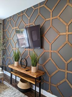 a tv mounted to the side of a wall next to a table with two plants on it