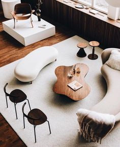 a living room filled with furniture next to a window and white rug on top of a hard wood floor