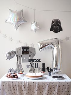 a star wars themed birthday party with silver foil balloons and stars on the wall above it