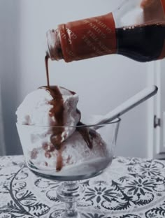 an ice cream sundae with chocolate sauce being poured into it