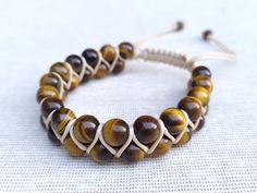 "Tiger's Eye Bracelet: Crafted with genuine tiger's eye gemstone beads, this natural healing crystal jewelry is perfect for men and women. All of the bracelets are personally handmade by me. I carefully select and use genuine natural stones and strong cords to create durable and beautiful pieces. Each piece is made to order and can be customized according to your preferences! Product Details - Handcrafted bracelet featuring 8mm tiger's eye beads. - Secured with a strong 1mm beige cord. - Finished with 6mm onyx beads as a stopper. * Tiger's Eye: Protection, courage, and personal power. Size - Adjustable options available for both Men and Women. - For Women: Fits wrists from 6\" to 7.5\" [15.2 cm - 19.1 cm] - For Men: Fits wrists from 7\" to 8.5\" [17.8 cm - 21.6 cm] - You can also choose a Natural Jewelry, Tiger Eye Bracelet, Healing Crystal Jewelry, Handcrafted Bracelets, Tigers Eye Gemstone, Tiger Eye Beads, Eye Beads, Personal Power, Onyx Bead