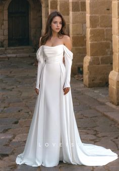 a woman in a white wedding dress standing on a stone walkway with her hands on her hips