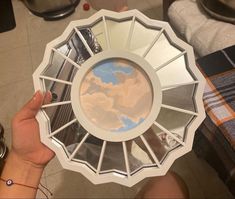 a person holding up a plate with the reflection of clouds in it's center