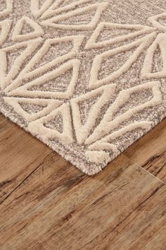 a beige and white rug on top of a wooden floor