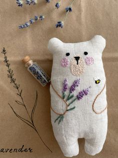 a stuffed bear with lavender flowers on it next to a bottle of lavender essential oil