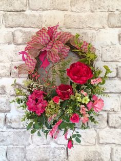 a wreath with pink and red flowers hanging on a brick wall