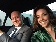 a man and woman sitting in the back seat of a car smiling at the camera