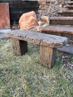 an old wooden bench sitting in the grass near some stairs and steps leading up to a building