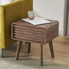 a small wooden table with a book and coffee cup on it next to a couch