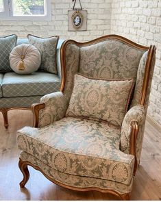 two chairs and a couch in a room with white brick walls, wood floors and wooden flooring