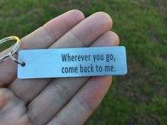 a hand holding a keychain that says wherever you go, come back to me