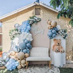 a teddy bear sitting on top of a white chair next to balloons and decorations in front of a house