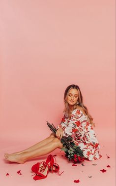 a woman sitting on the ground with her legs crossed and flowers in front of her