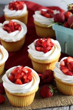 several cupcakes with white frosting and strawberries on the top are sitting on a mat