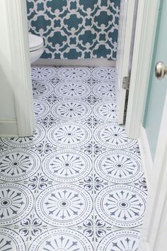 a white toilet sitting next to a blue and white tiled bathroom floor with an open door