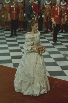 a woman in a wedding dress standing on a checkered floor with other men and women