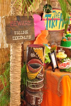 there is a tiki statue next to a sign that says beware falling coconuts