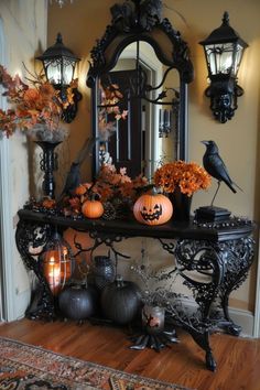 a table with pumpkins and candles on it in front of a mirror, decorated for halloween