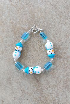 "Beaded handmade bracelet, snowman jewelry, pearl holiday jewelry, Christmas holiday bracelet, cute holiday jewelry for women, teens Sterling silver, glass snowmen, crystal and glass pearl Handmade Bracelet, 7.25\" all snowmen beads are approx 19mm long. 2mm round beads are sterling silver. Glass pearl beads are 5mm, Blue Glass beads are 8mm long by 5mm wide. Czech crystals are 2mm clear ab. Toggle clasp is pewter. Check out my other jewelry at https://loveofjewelryshop.etsy.com" Snowman Jewelry, Beaded Snowflake Bracelet, Winter Bracelet, Turquoise Ocean-inspired Bracelet With Lobster Clasp, Holiday Bracelets, Nickel-free Blue Crystal Bracelet With Round Beads, Christmas Bracelet, Xmas Holidays, Toggle Bracelet