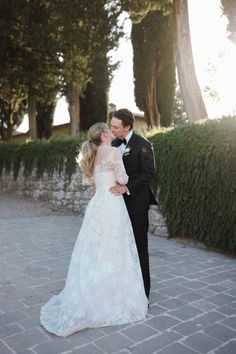 a bride and groom standing in front of some trees