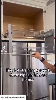 a man pointing to the bottom of a stainless steel refrigerator