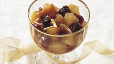 a glass filled with fruit and nuts on top of a table next to a yellow ribbon