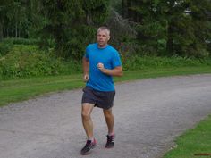 a man running down a dirt road with trees in the background