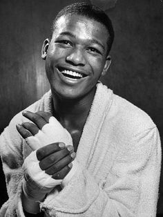 a black and white photo of a smiling man holding a baby wrapped in a towel