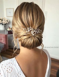 a woman with blonde hair in a low bun and a flowered headpiece is seen from the back