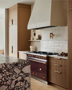 a stove top oven sitting inside of a kitchen next to wooden cabinets and counter tops