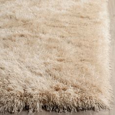 a shaggy rug on the floor with wood floors in the background and light brown tones