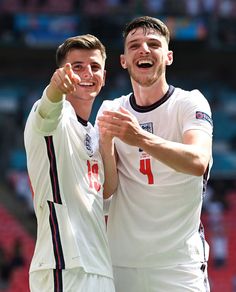 two men standing next to each other in front of a crowd at a soccer game