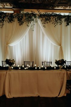 the table is set up with white flowers and greenery for an elegant wedding reception